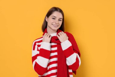 Beautiful woman in warm scarf on yellow background