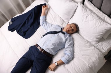 Businessman in office clothes sleeping on bed indoors, top view