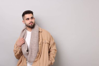 Açık gri arka planda, sıcak eşarplı yakışıklı bir adam. Metin için boşluk