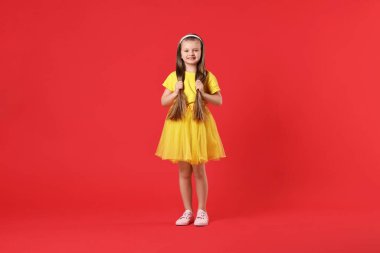 Kırmızı arka planda uzun saçlı şirin bir dansçı.