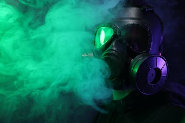 Gaz maskesi takan adam siyah arka planda duman çıkarıyor. Metin için boşluk