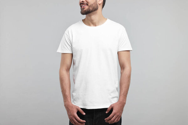 Smiling man in white t-shirt on grey background, closeup