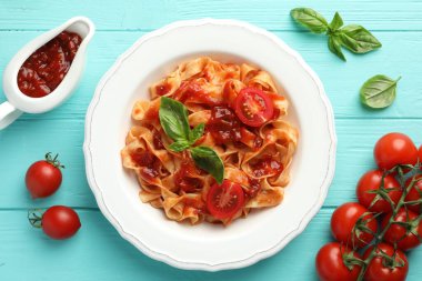 Domates soslu lezzetli makarna ve turkuaz ahşap masada fesleğen.