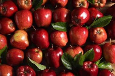 Fresh ripe red apples with leaves on wooden table, flat lay