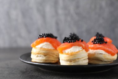 Krem peynirli lezzetli puf böreği, somon balığı ve gri masada siyah havyar.