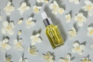 Temel yağ şişede ve güzel yasemin çiçekleri gri arka planda, düz yatıyordu.