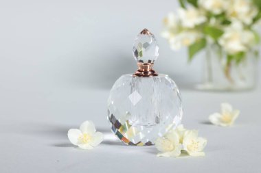 Şişede Aromatik parfüm ve gri arka planda güzel yasemin çiçekleri, yakın plan.