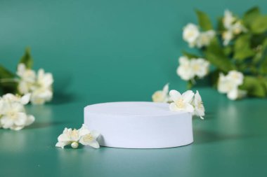 Ürünün sunumu. Beyaz podyum ve yeşil arka planda güzel yasemin çiçekleri