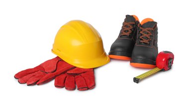 Bir çift çalışma botu, koruyucu eldiven ve beyaz üzerine izole edilmiş mezura.