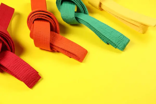 stock image Colorful karate belts on yellow background, space for text