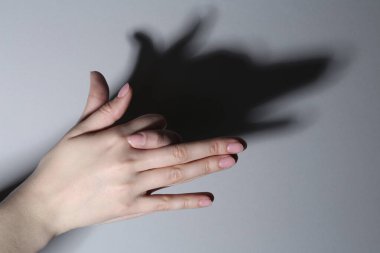 Gölge kuklası. Kadın, gri arka planda köpek gibi el hareketi yapıyor, yakın plan.
