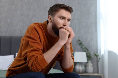Yalnızlık kavramı. Evdeki yatakta oturan üzgün adam.