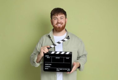 Film çekiyoruz. Yeşil arka planda alkışlarla gülümseyen adam.