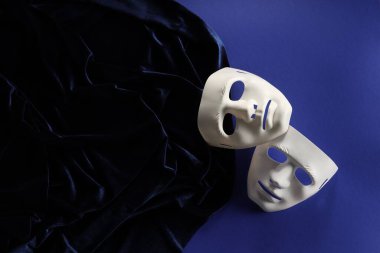 Tiyatro sanatları. Mavi arka planda beyaz maskeler ve kumaşlar, üst görünüm