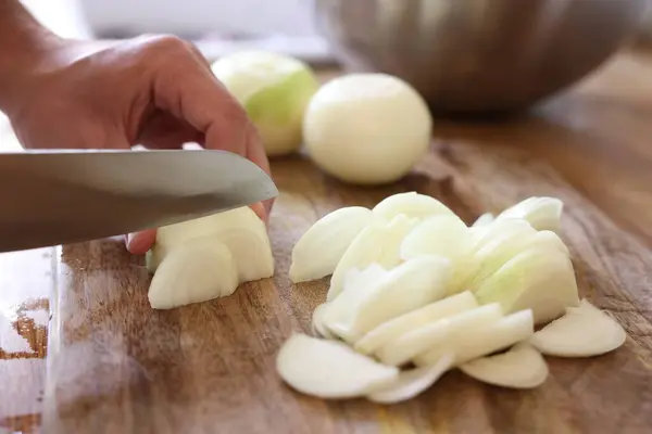 Stock image Woman cutting fresh ripe onion on wooden board, closeup