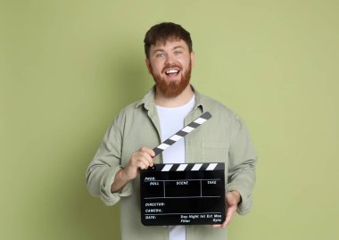 Film çekiyoruz. Yeşil arka planda alkışlarla gülümseyen adam.