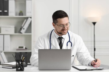 Doktorun klinikteki masada dizüstü bilgisayarla danışması