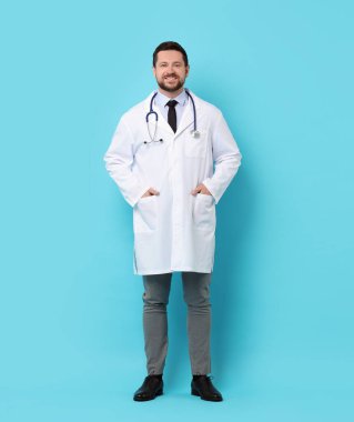 Açık mavi arka planda steteskoplu gülümseyen doktor.