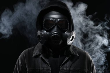 Siyah arka planda gaz maskesi takan adam.