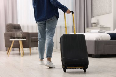Bavullu bir misafir otel odasında yürüyor, yakın plan.