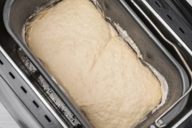 Masanın üstünde çiğ hamurlu ekmek makinesi var.