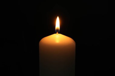 Siyah arka planda yanan bir kilise mumu, yakın plan.