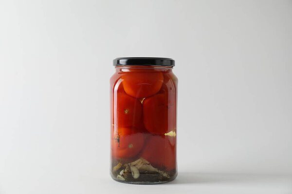 Вкусные маринованные помидоры в банке на светло-сером фоне