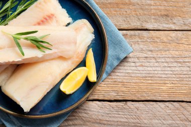 Çiğ balık parçaları, ahşap masada biberiye ve limon, üst manzara. Metin için boşluk