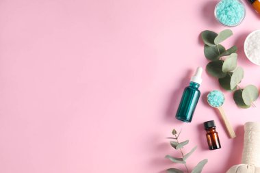 Pembe arka planda farklı aromaterapi ürünleri ve okaliptüs dalları. Metin için boşluk