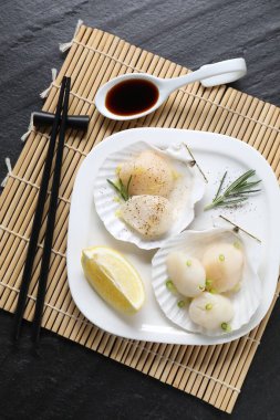 Yeşil soğanlı çiğ istiridye, biberiye, limon ve soya sosu koyu dokulu masa, üst görünüm