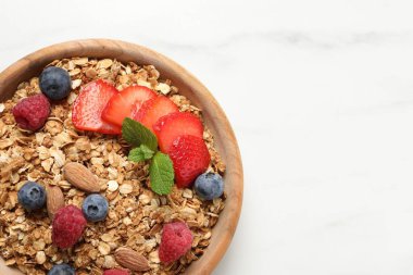 Böğürtlenli tahıl gevreği, fındık ve nane, beyaz masa, üst manzara. Metin için boşluk