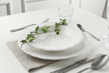 Beyaz desenli masa üzerindeki çatal bıçak ve tabaklarla şık bir ortam.