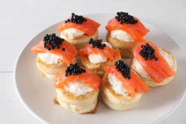 Krem peynirli lezzetli puf böreği, somon balığı ve siyah havyar beyaz masada, yakın plan.