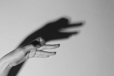 Gölge kuklası. Kadın hafif arka plandaki kaz gibi el hareketi yapıyor, mesaj için yer ararken yakın plan çekiyor. Siyah ve beyaz etkisi