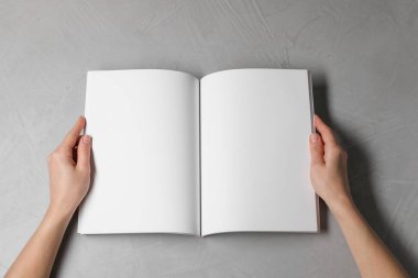 Açık gri masada elinde boş sayfaları olan bir defter tutan kadın. Tasarım için model