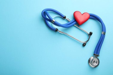 Stetoskop ve açık mavi arka planda kırmızı kalp, üst manzara. Metin için boşluk