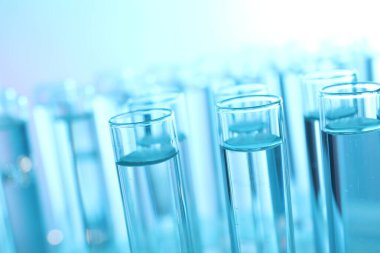 Açık mavi arka planda birçok cam test tüpü, yakın plan
