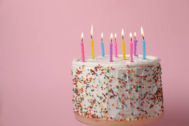 Pembe arka planda yanan mumları olan Lezzetli Doğum günü pastası, metin için yer