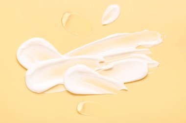 Soluk sarı arka planda yüz kremi örnekleri, üst manzara.