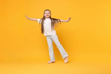 Sarı arka planda dans eden tatlı küçük kız, mesaj için yer var.