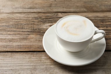 Kahve fincanında kapuçino, ahşap masada, yakın plan. Metin için boşluk