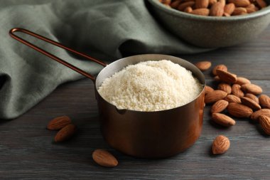 Kepçe içinde taze badem unu ve ahşap masada fındıklar, yakın plan.