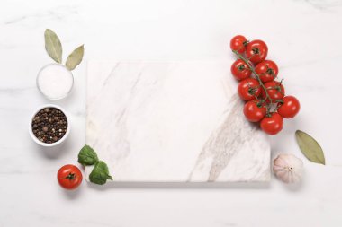Kesme tahtası, baharatlar ve domatesler beyaz mermer masada, düz yerde. Metin için boşluk