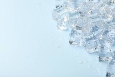 Açık mavi arka planda kristal berrak buz küpleri, yakın plan. Metin için boşluk