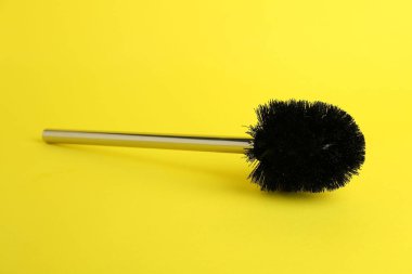 Sarı arka planda bir tuvalet fırçası. Temizlik aracı