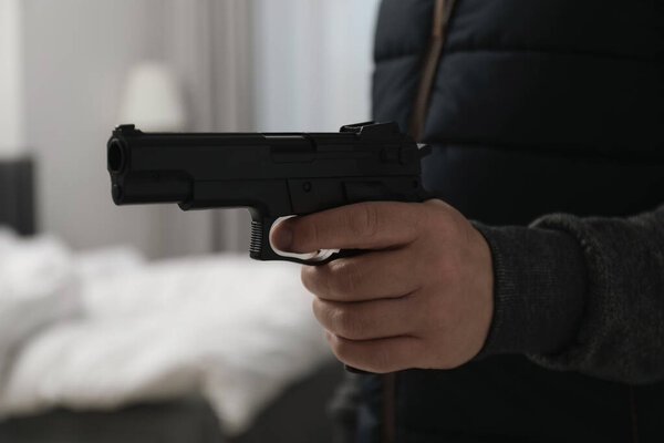 Dangerous criminal with gun indoors, closeup. Armed robbery