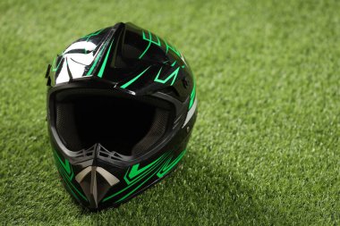 Yeşil çimlerin üzerinde güneşliği olan modern motosiklet kaskı, metin için alan