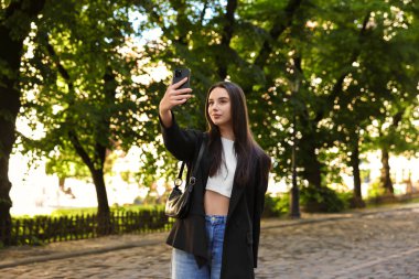 Gezgin blogcu dışarıda akıllı telefonuyla selfie çekiyor.