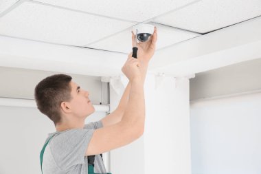 Tornavidalı teknisyen kapalı alanda güvenlik kameraları yerleştiriyor.