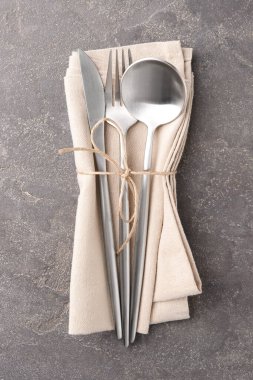 Gri desenli masa üzerinde şık çatal bıçak seti ve peçete.